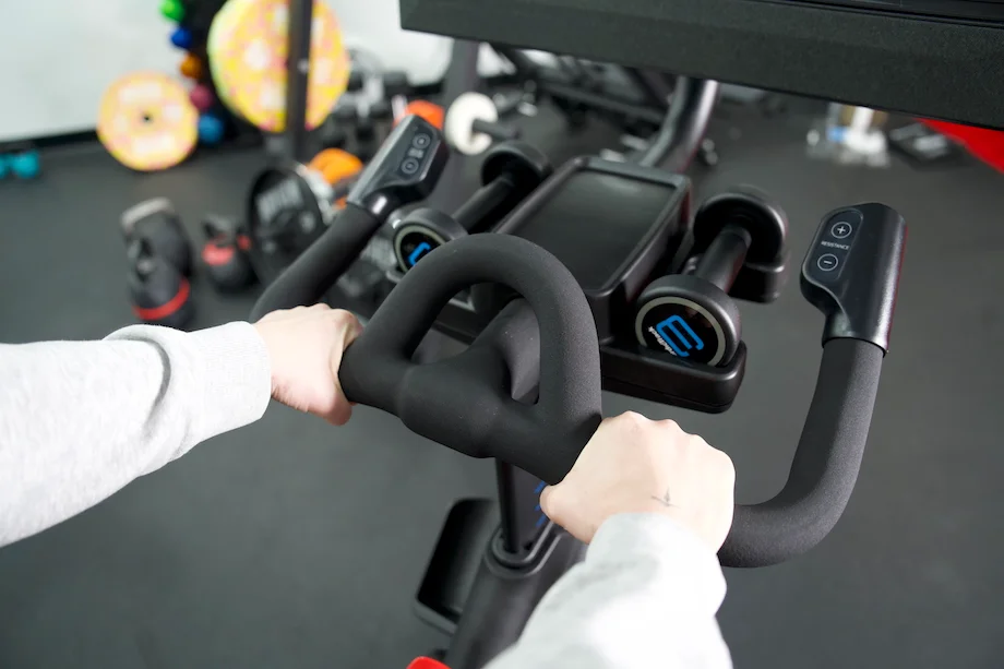 Close view of a woman holding the handlebars on the NordicTrack X24 bike 