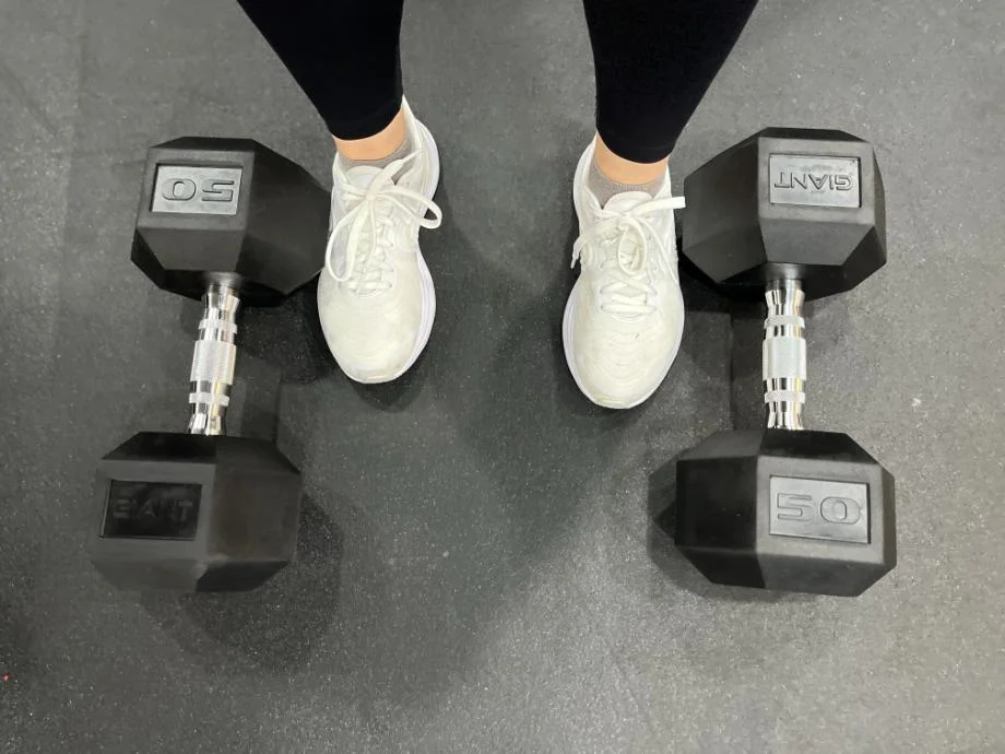 Person standing with Giant Lifting Hex Dumbbells on either side of their feet