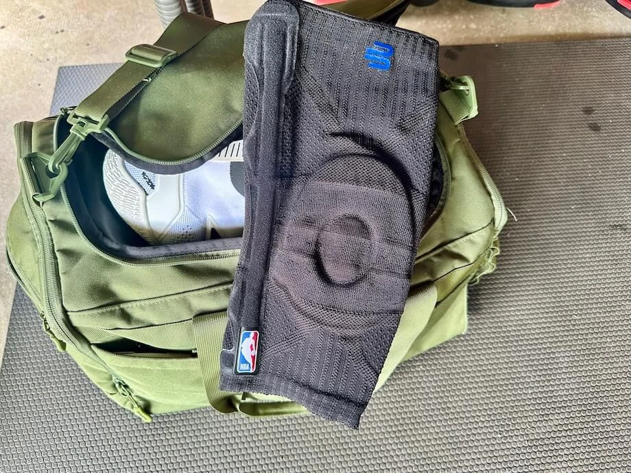 A Bauerfeind Sports Knee Support lays on a sports bag