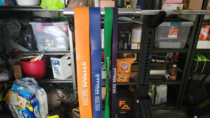 A set of Titan Fitness Heavy Resistance Bands hanging from a bar in a gym