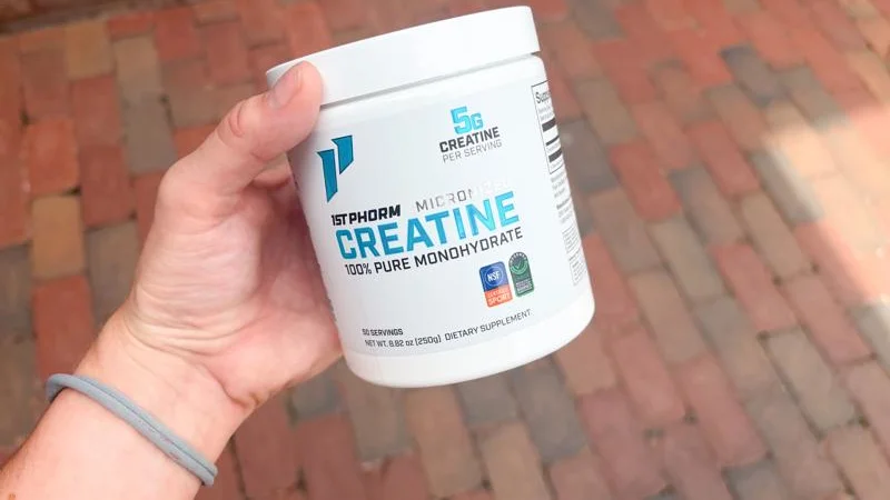 A product tester holding a tub of 1st Phorm Micronized Creatine Monohydrate