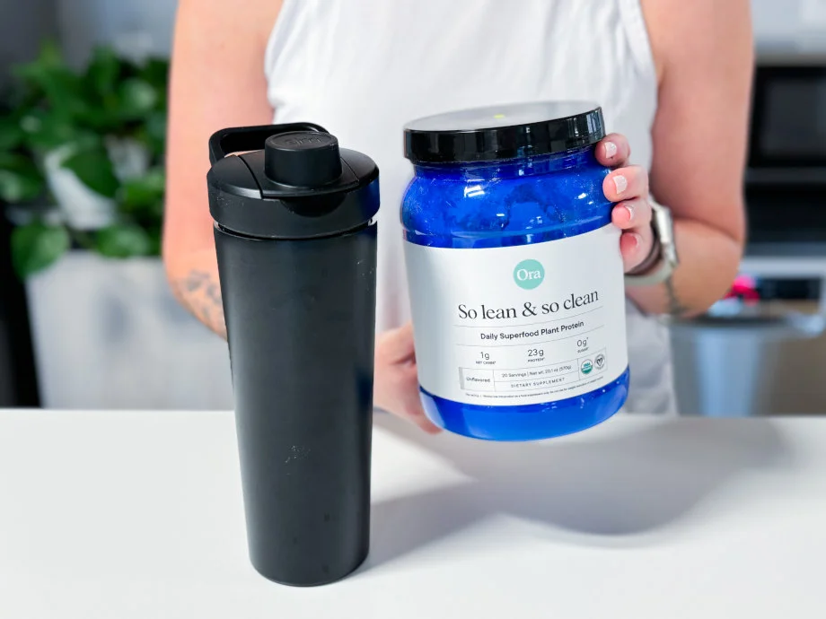 Our tester holds up a container of Ora Organics So Lean & So Clean Plant Based Superfood Protein