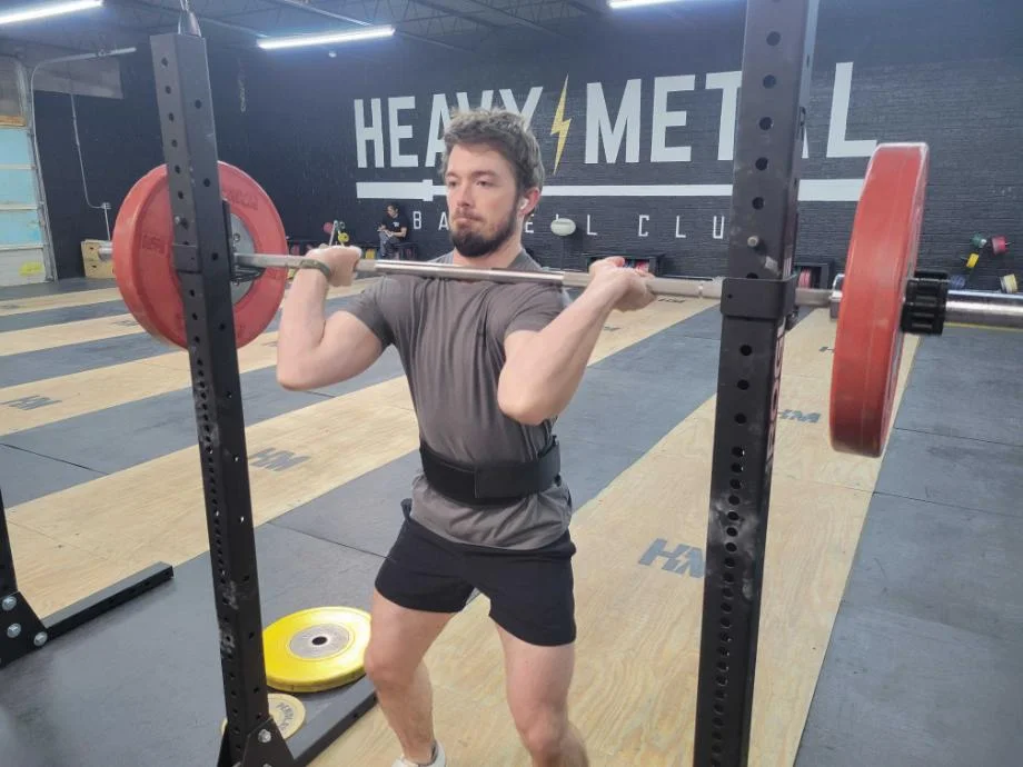 A man starts a front squat while using the Warm Body Cold Mind Weightlifting Belt