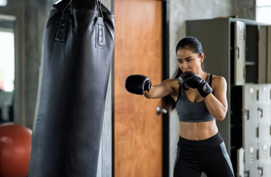 A woman punches a punching bag.