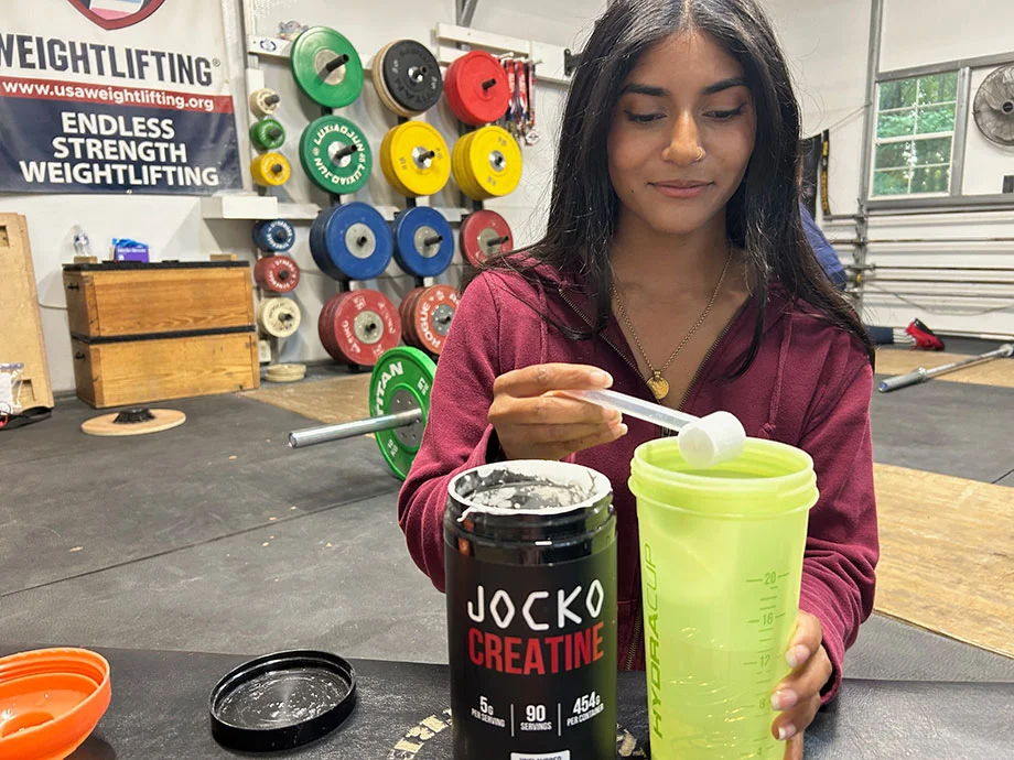 person mixing jocko creatine into shaker cup