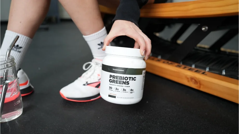 Someone holding a Transparent Labs Prebiotic Greens container near the floor
