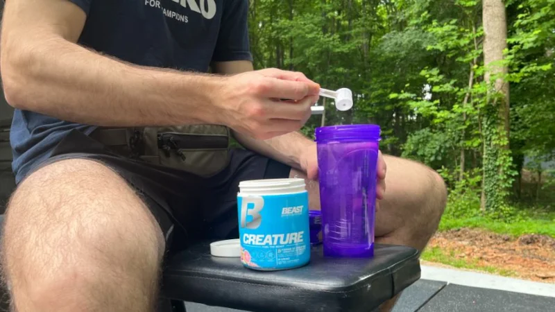 Man scooping Beast Creatine into a shaker cup