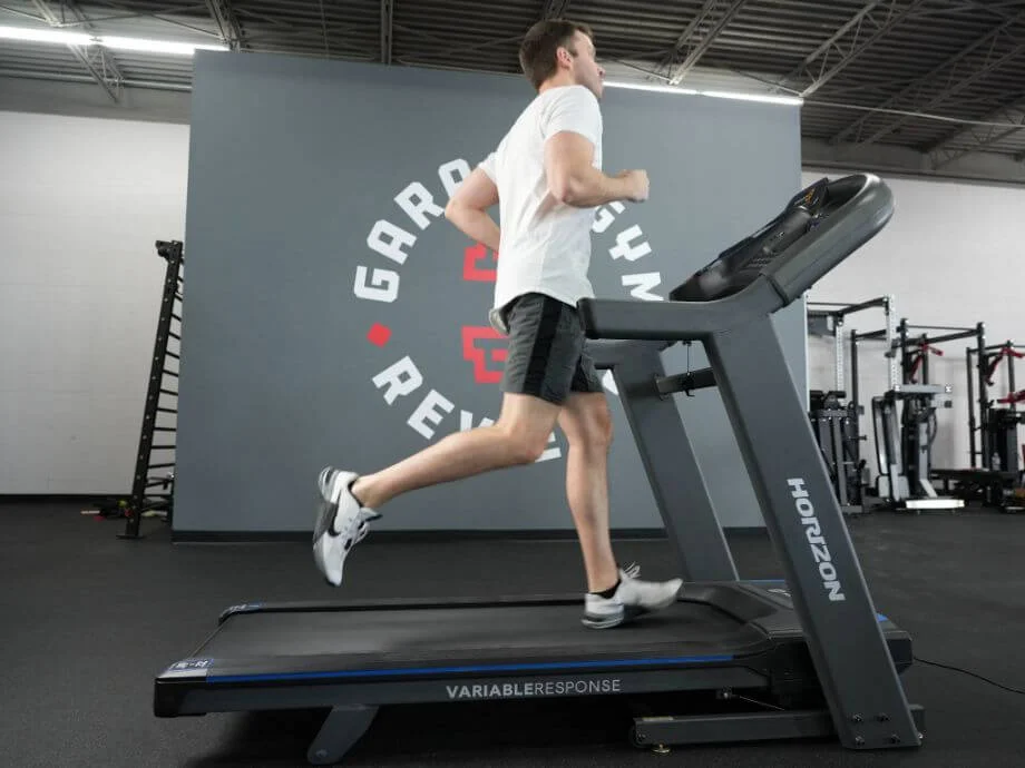 Person in shorts and a white t-shirt running on a Horizon 7.4 treadmill
