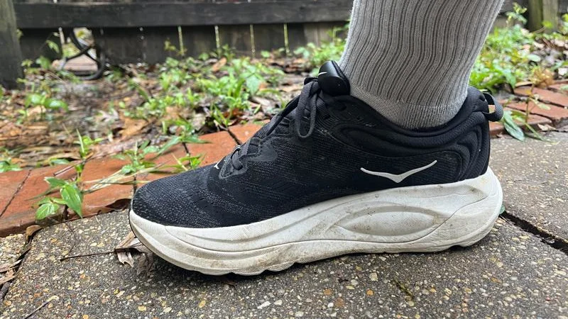 Side view of a person wearing a pair of HOKA Gaviota 6 recovery shoes.
