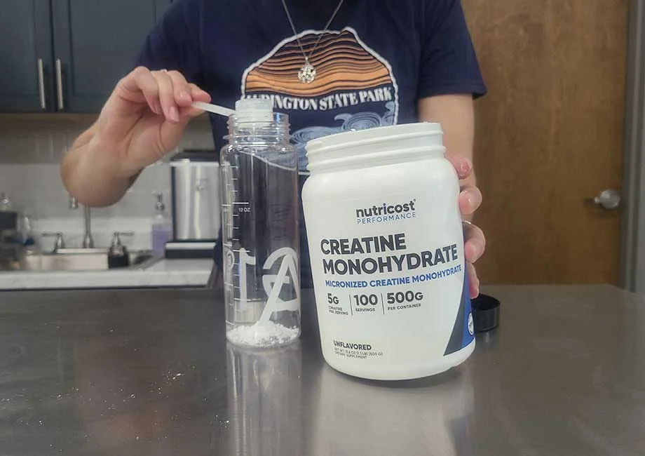 dumping-scoop-of-nutricost-creatine Someone dumping a scoop of Nutricost Creatine into a shaker