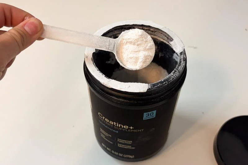 A tester takes a scoop of Factor Form Creatine+ out of its container