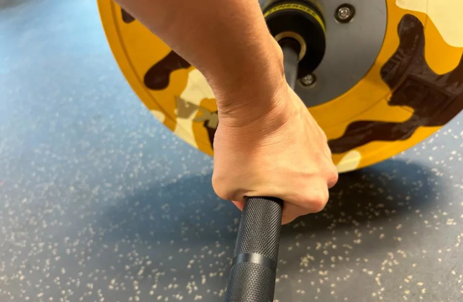 A person is shown gripping the knurling of a Synergee Games Barbell
