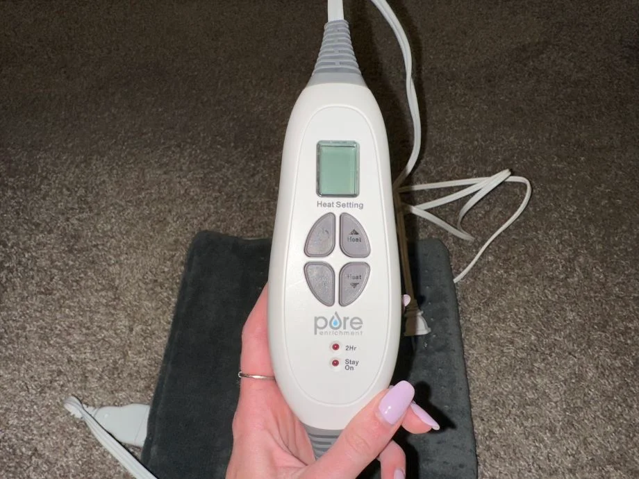 A person holds the controller for a Pure Enrichment XI Heating Pad