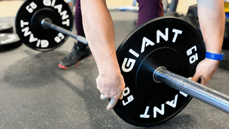Our tester loading 10-pound GIANT Lifting Base Bumper Plates onto a barbell