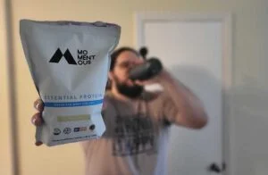 man holding bag of momentous essential whey protein