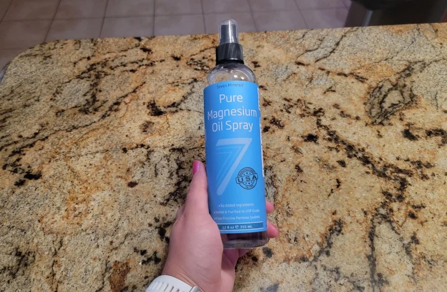 hand holding pure magnesium oil spray showing front of bottle