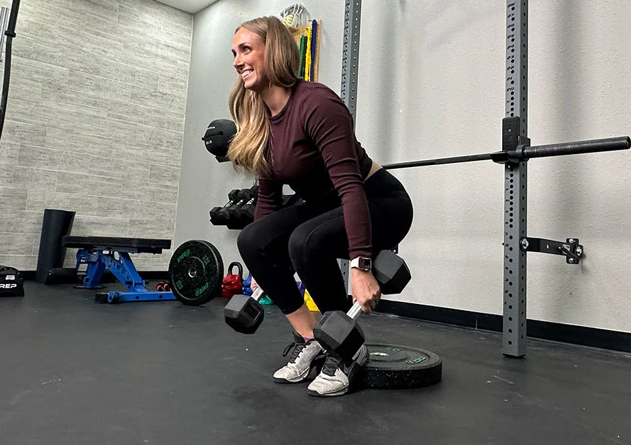 woman-performing-heels-elevated-dumbbell-hack-squat
