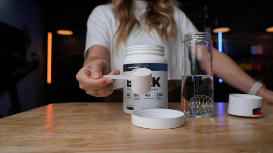 A woman holds a scoop of Transparent Labs BULK