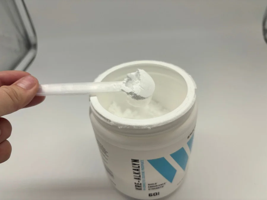A person lifting a scoop of Swolverine Kre-Alkalyn creatine. 