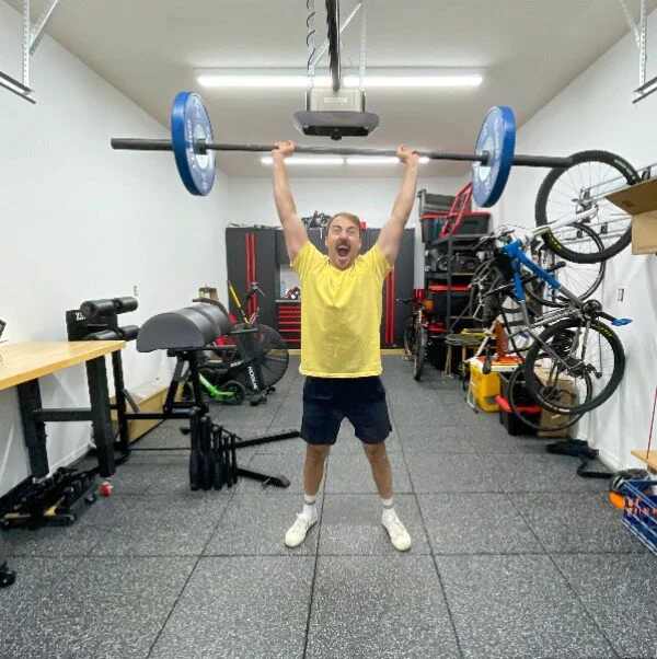 Coop lifting a barbell under the LiftMaster