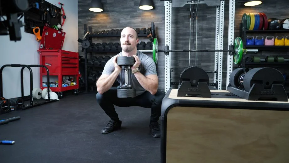 Man performing a goblet squat using one of the best dumbbells: the Snode AD80 adjustable dumbbells