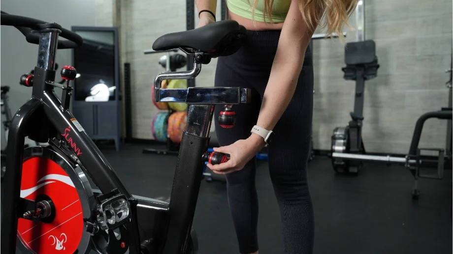 GGR Everything lead reviewer Lindsay Scheele adjusting the seat on the Sunny Health and Fitness B1002 exercise bike.
