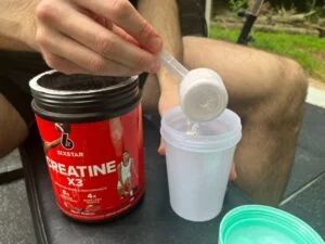 six star creatine man scooping in cup