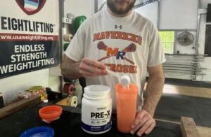 man pouring scoop of nutricost pre x pre workout