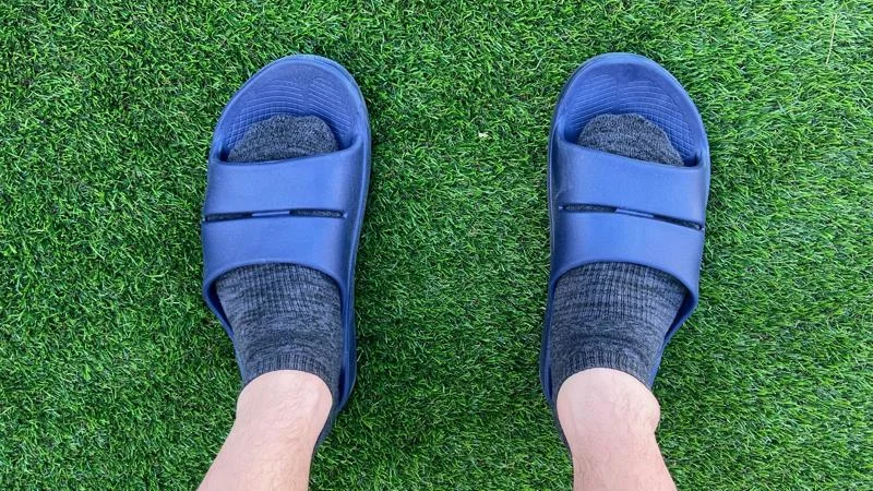 A person wearing a pair of OOFOS OOahh Slides.