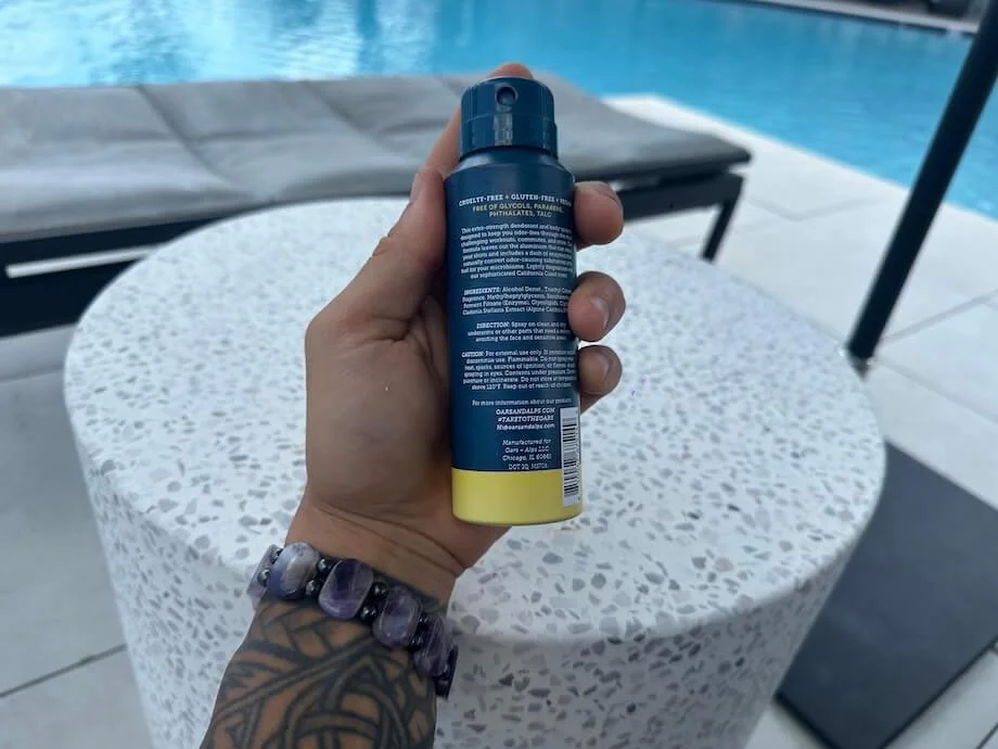 A hand holds a can of Oars + Alps Aluminum-Free Deodorant Spray