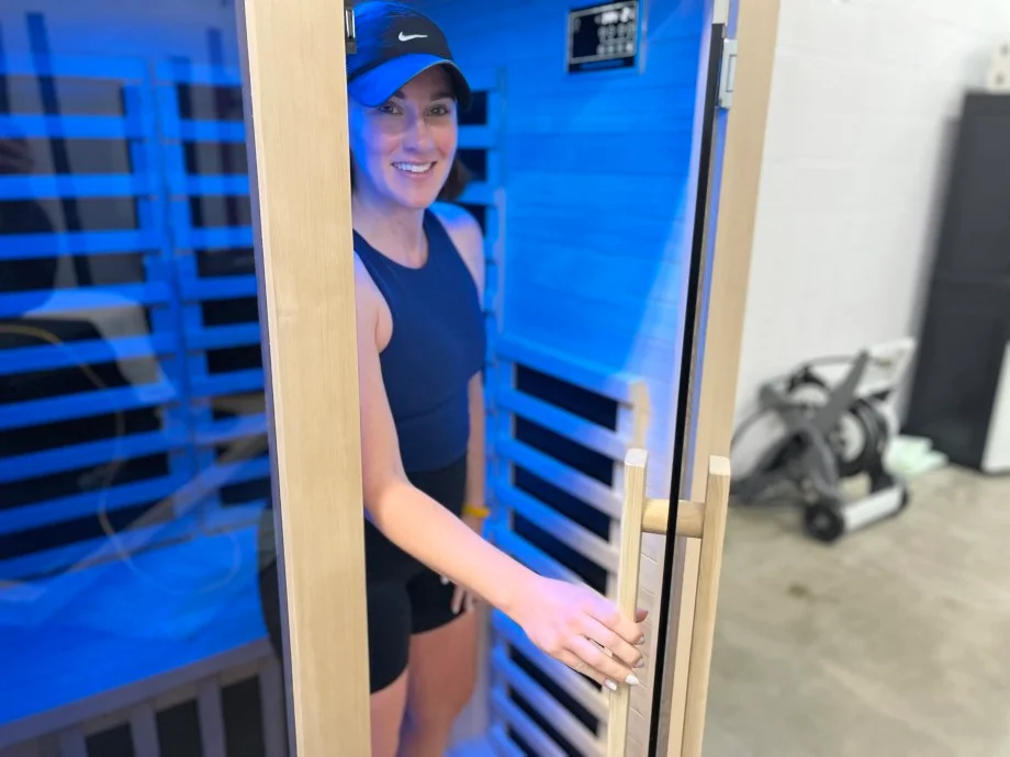 A woman smiles from inside the door of a Heavenly Heat 1-Person Sauna