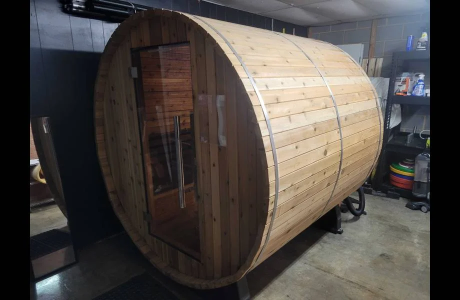 exterior view of almost heaven morgan barrel sauna located inside a garage with the door closed