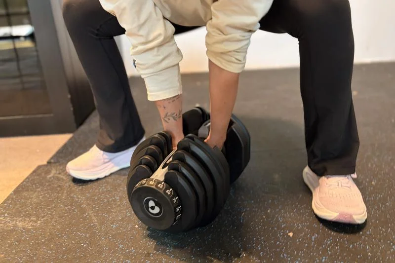 A woman performing a deadlift with the Bowflex Results Series 1090 SelectTech Adjustable Dumbbells
