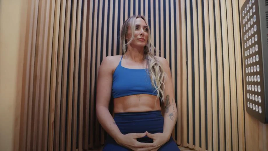 Expert tester Lindsay Scheele, CPT, sits with her hands in a meditative mudra in a Sun Home Pod Sauna.