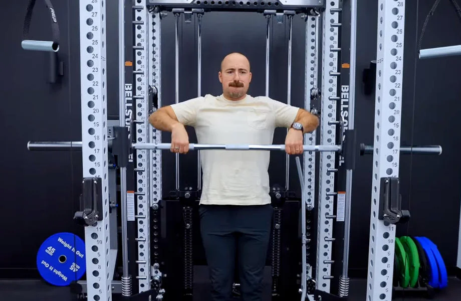 A man is shown working out with the Bells of Steel Smith Machine Attachment