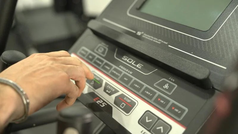A person using the controls on the Sole E25 Elliptical