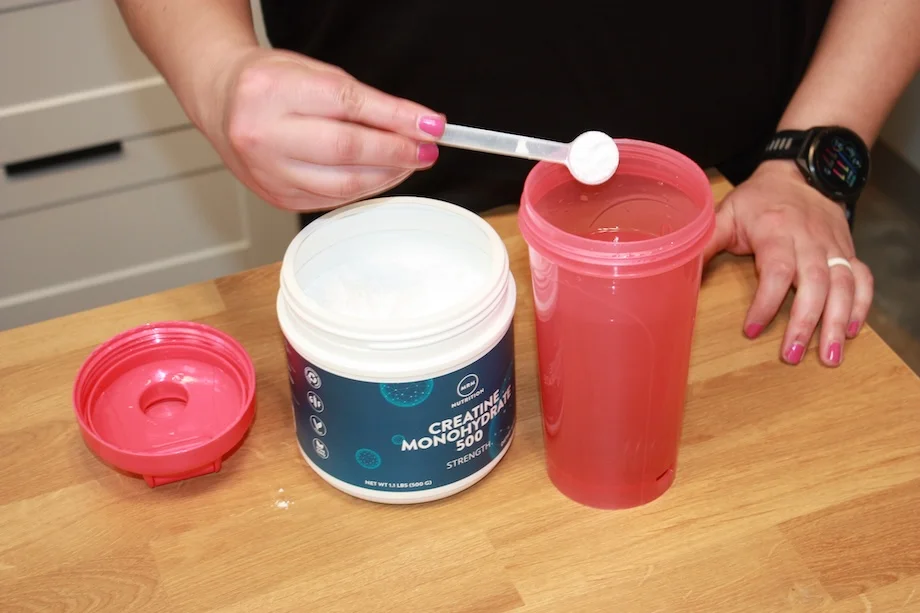 Product tester scooping MRM Nutrition Creatine into a shaker cup