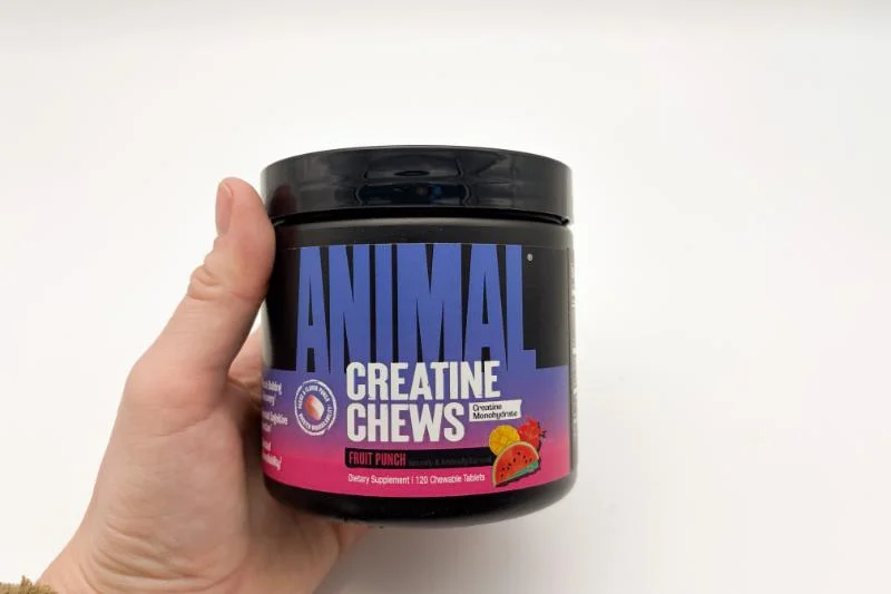A person holding a container of Animal Creatine Chews