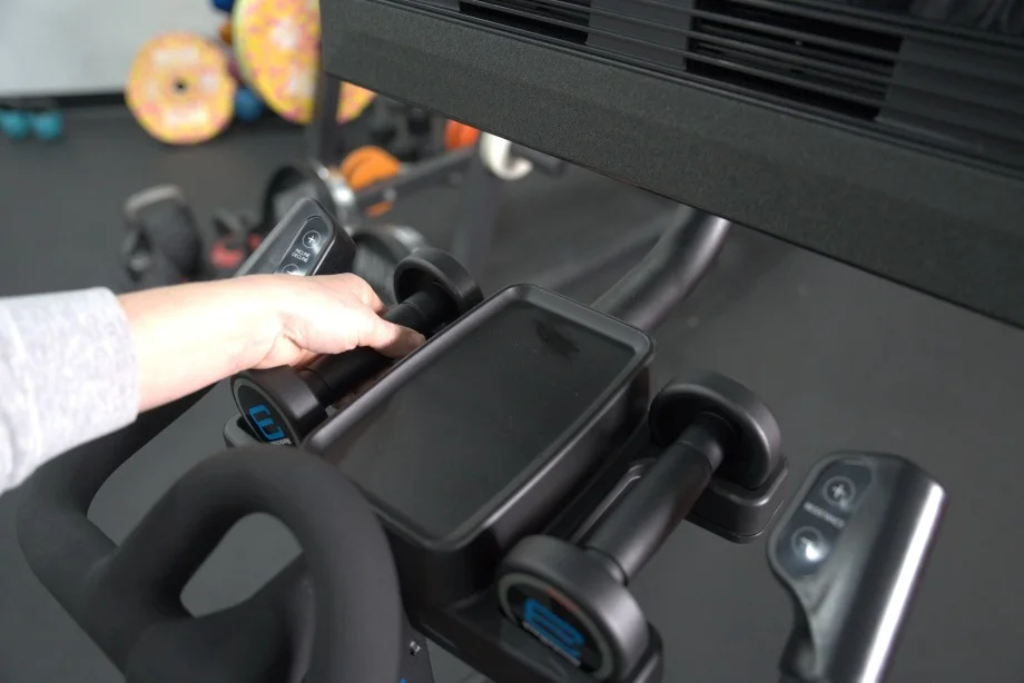 A person lifts a dumbbell from the cradle on a NordicTrack X24 Bike.