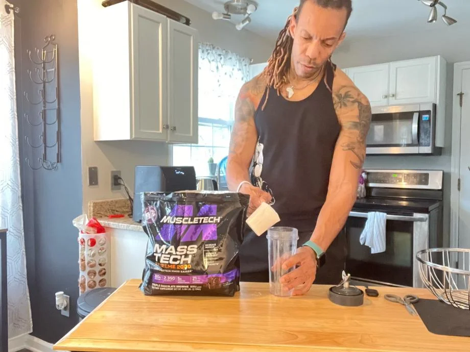 person putting muscle tech mass gainer in cup