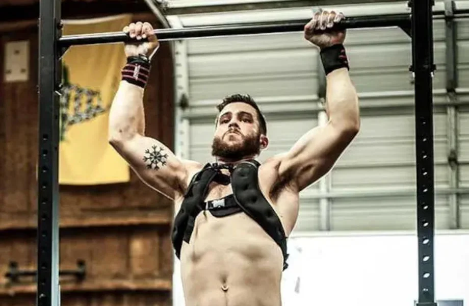 An athlete performing a pull-up while wearing a Fringe Sport WODMaster Weight Vest