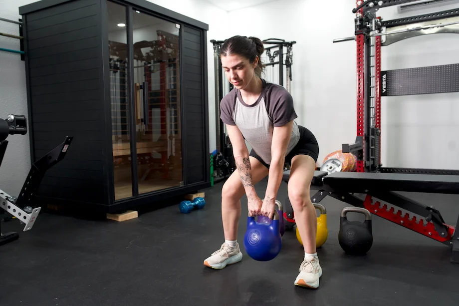 Woman performs a sumo deadlift using the Bells of Steel Adjustable Kettlebell