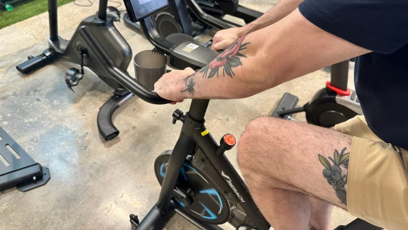ggr-merach-36s-magnetic-exercise-bike-tester-gripping-handlebars A product tester gripping the handlebars of a MERACH 36S Magnetic Exercise Bike