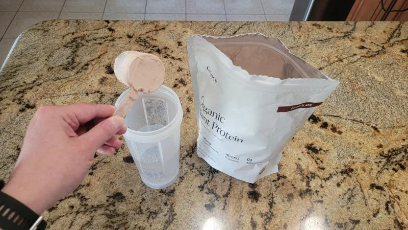 Our tester scoops Quince Organic Plant Protein Powder into a shaker cup