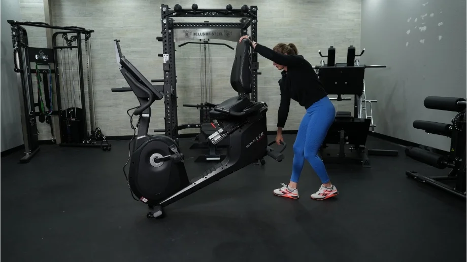 Full view of the Sole LCR Recumbent Bike while a person lifts it.