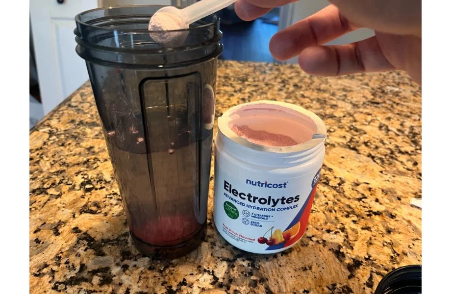 man_scooping_nutricost_electrolyte_powder_into_cup 1