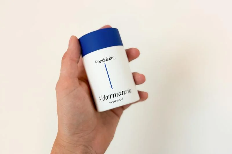 A product tester holding a container of Pendulum Akkermansia