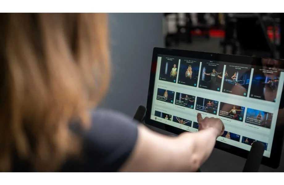 A woman using the touchscreen on the Peloton bike