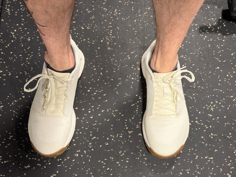 Looking down at the feet of a person wearing a pair of NOBULL Outwork Flex cross-training shoes.