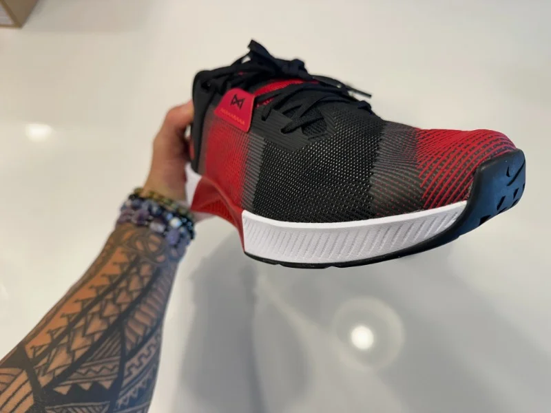 A person holds up a Nike Metcon 10 gym shoe